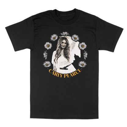 A black short-sleeve crewneck t-shirt featuring a front graphic print of Carly Pearce surrounded by white daisies, with her name printed in yellow at the bottom.